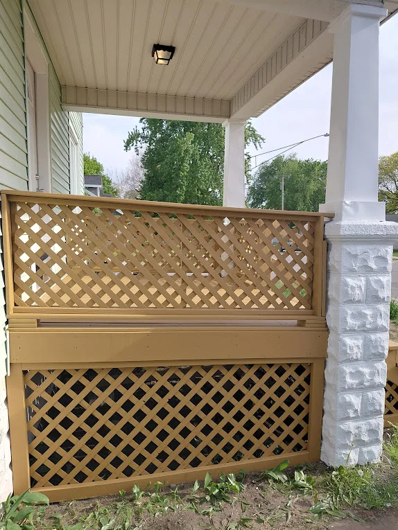 Covered porch with white ceiling beams and columns beside a natural wood lattice privacy screen