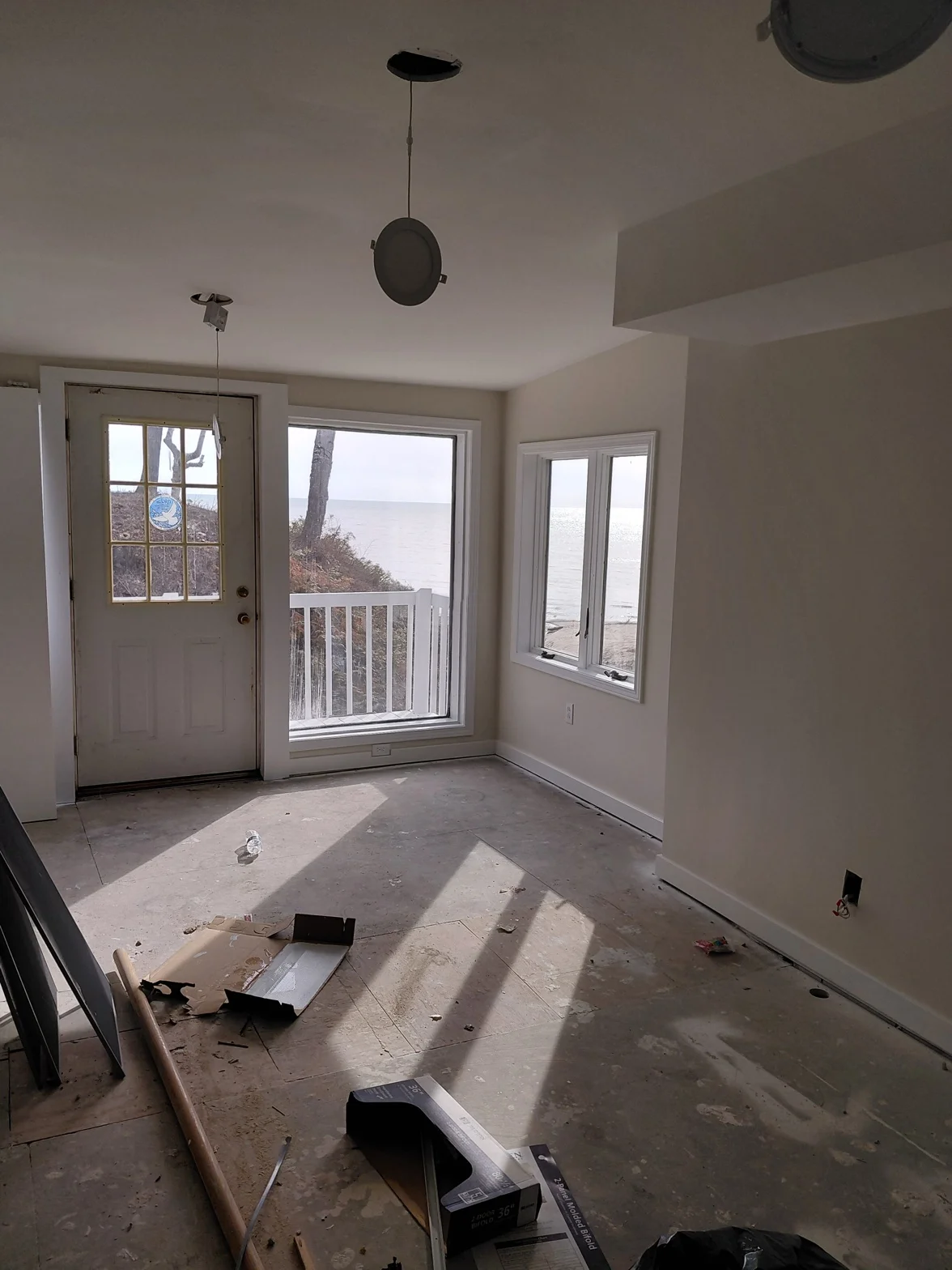 Sunlit interior room with freshly finished white walls, large windows, and waterfront views