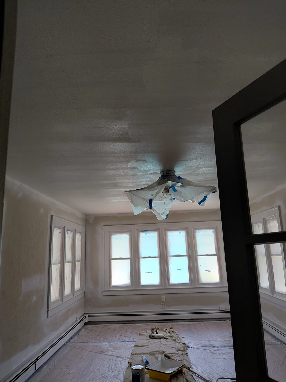Interior room protected with drop cloths and prepped before painting, walls bare and ready